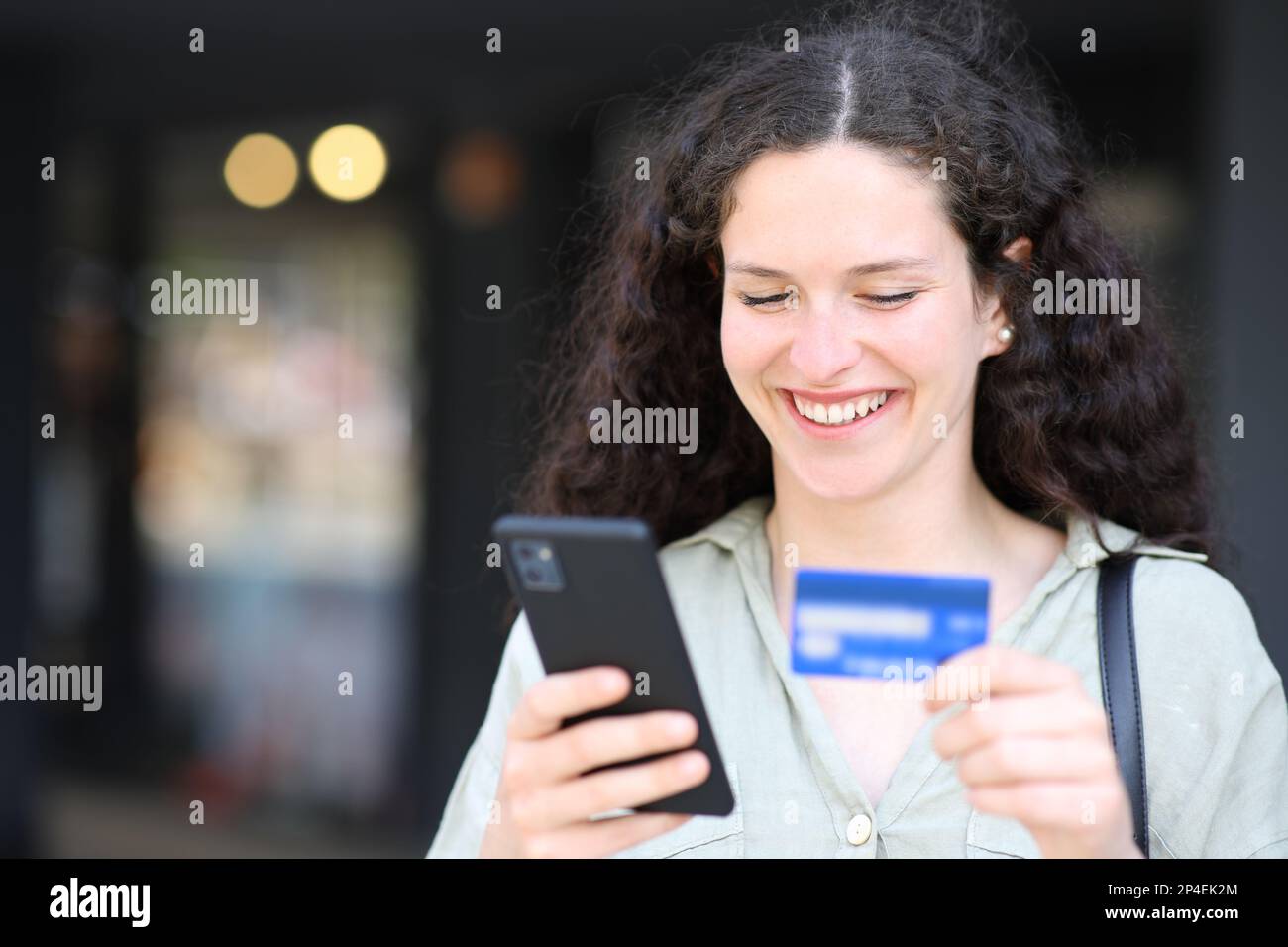 Femme achetant en ligne dans la rue avec carte de crédit et téléphone Banque D'Images