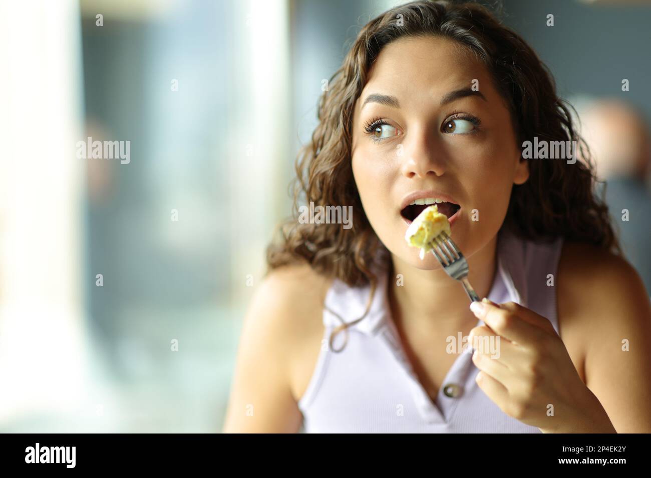 Vue de face d'une femme mangeant une omelette en regardant à côté dans un restaurant Banque D'Images