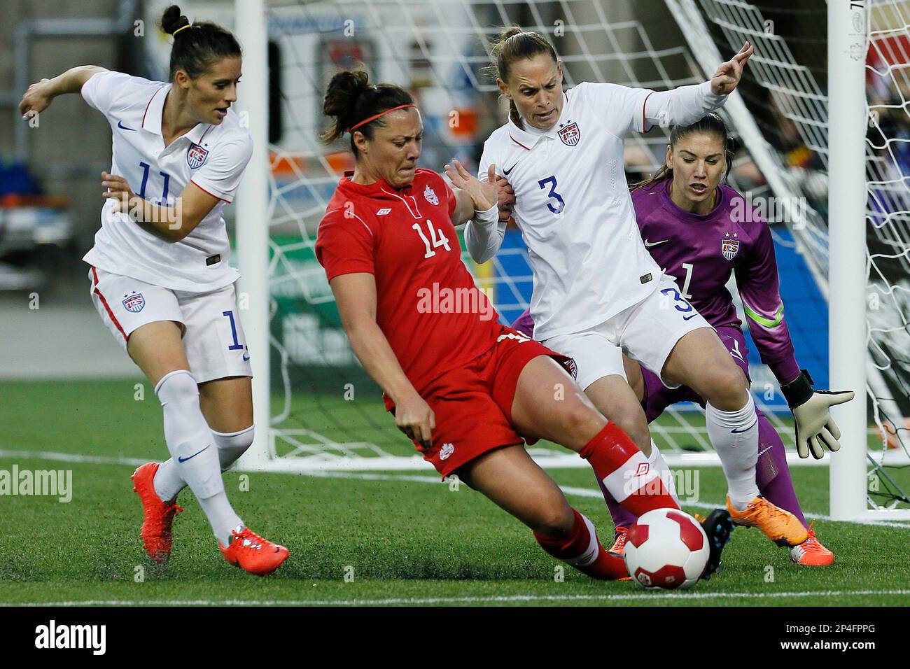 Canada's forward Melissa Tancredi (14) drives for the net as USA's goalkeeper Hope Solo (1) looks on as defenders Ali Krieger (11) and Christie Rampone (3) defend during the second half of an exhibition soccer match in Winnipeg, Manitoba, Thursday, May 8, 2014. (AP Photo/The Canadian Press, John Woods) Banque D'Images
