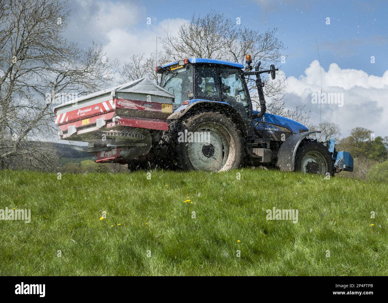 Tracteur avec épandeur, épandage d'engrais granulé sur les prairies, Castle Bolton, Redmire, North Yorkshire, Angleterre, Royaume-Uni Banque D'Images