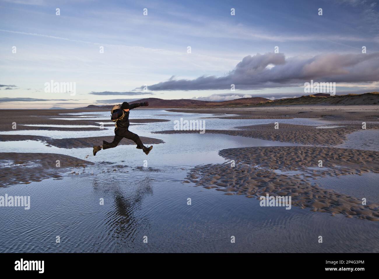 Homme sautant au-dessus des flaques de mer marécageux, Killinalan point, Loch Gruinart, île d'Islay, Hébrides intérieures, Écosse, Royaume-Uni Banque D'Images
