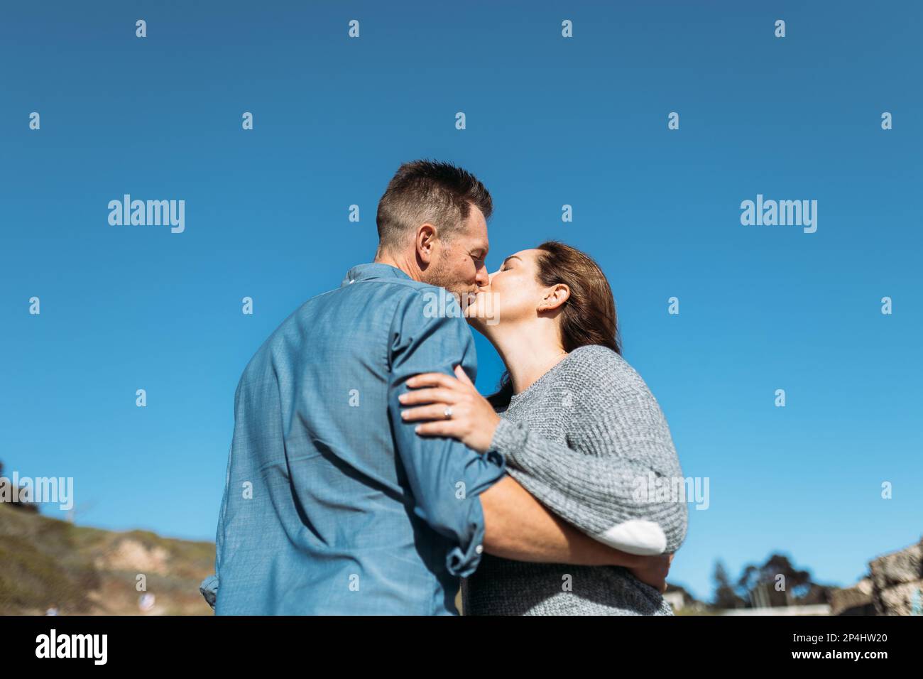 Les parents s'embrasser à la plage le temps d'un soleil Banque D'Images