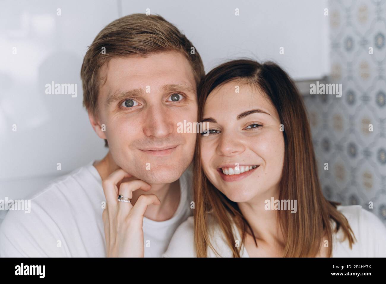 Gros plan d'un couple souriant d'amoureux sur une cuisine blanche Banque D'Images