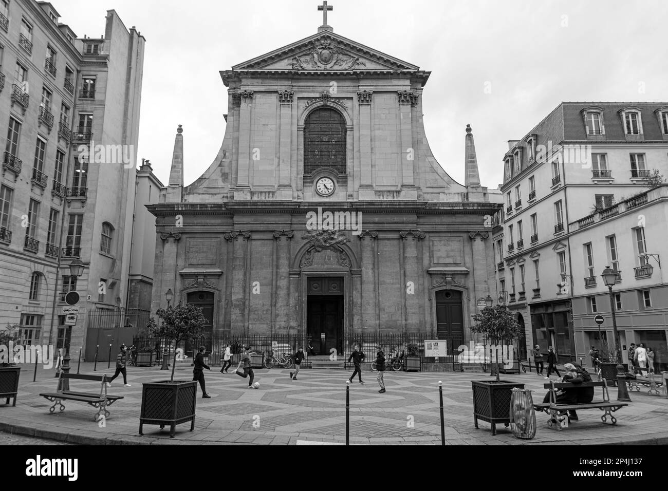 Photo en noir et blanc de garçons jouant au football devant la basilique notre-Dame des victoires, dans le 2nd arrondissement de Paris. Banque D'Images