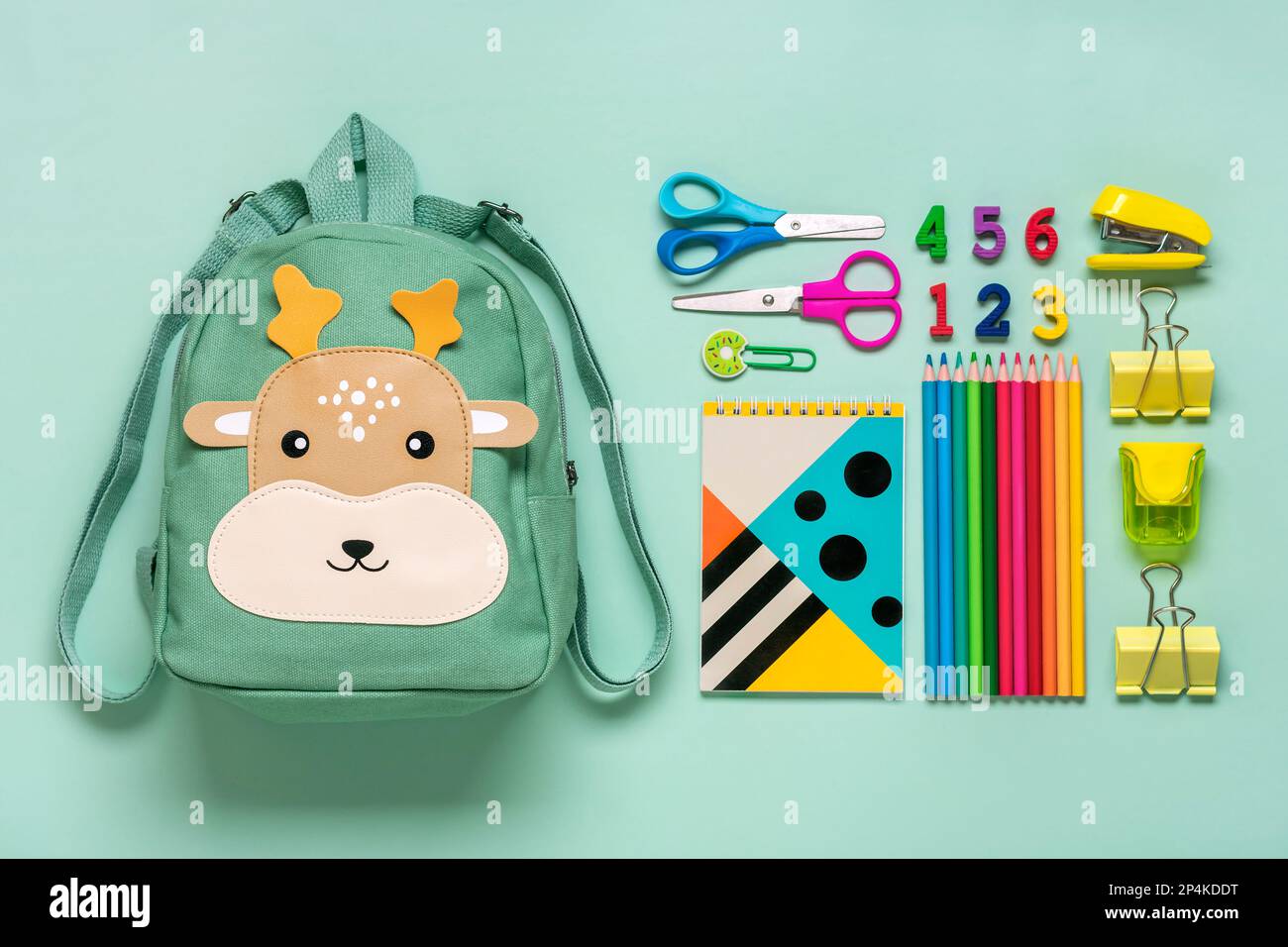 Retour à l'école, concept d'éducation Sac à dos Deer avec fournitures scolaires - bloc-notes, stylos, gomme arc-en-ciel, nombres isolés sur fond bleu vue du dessus Co Banque D'Images