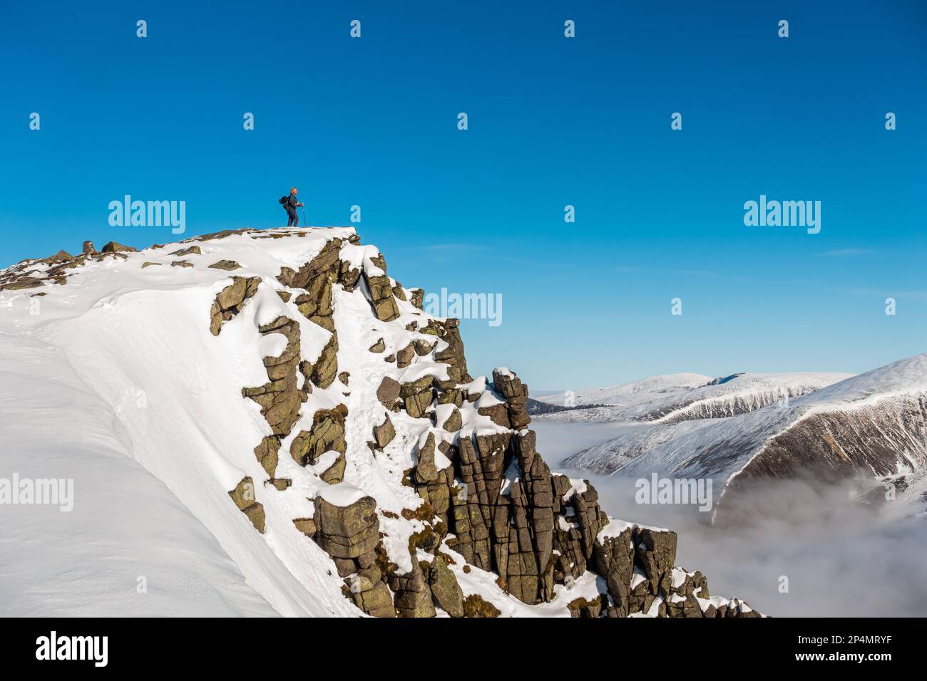 Un marcheur vu sur le sommet de la montagne écossaise Munro de Sgor Gaoith en hiver Banque D'Images