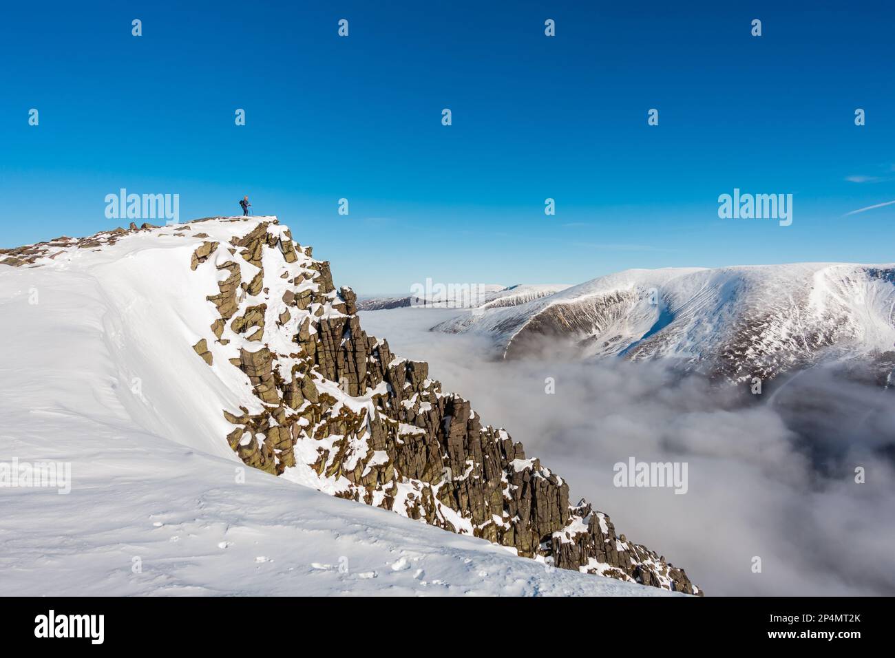 Un marcheur vu loin à gauche sur le sommet de la montagne Scottish Munro de Sgor Gaoith en hiver Banque D'Images