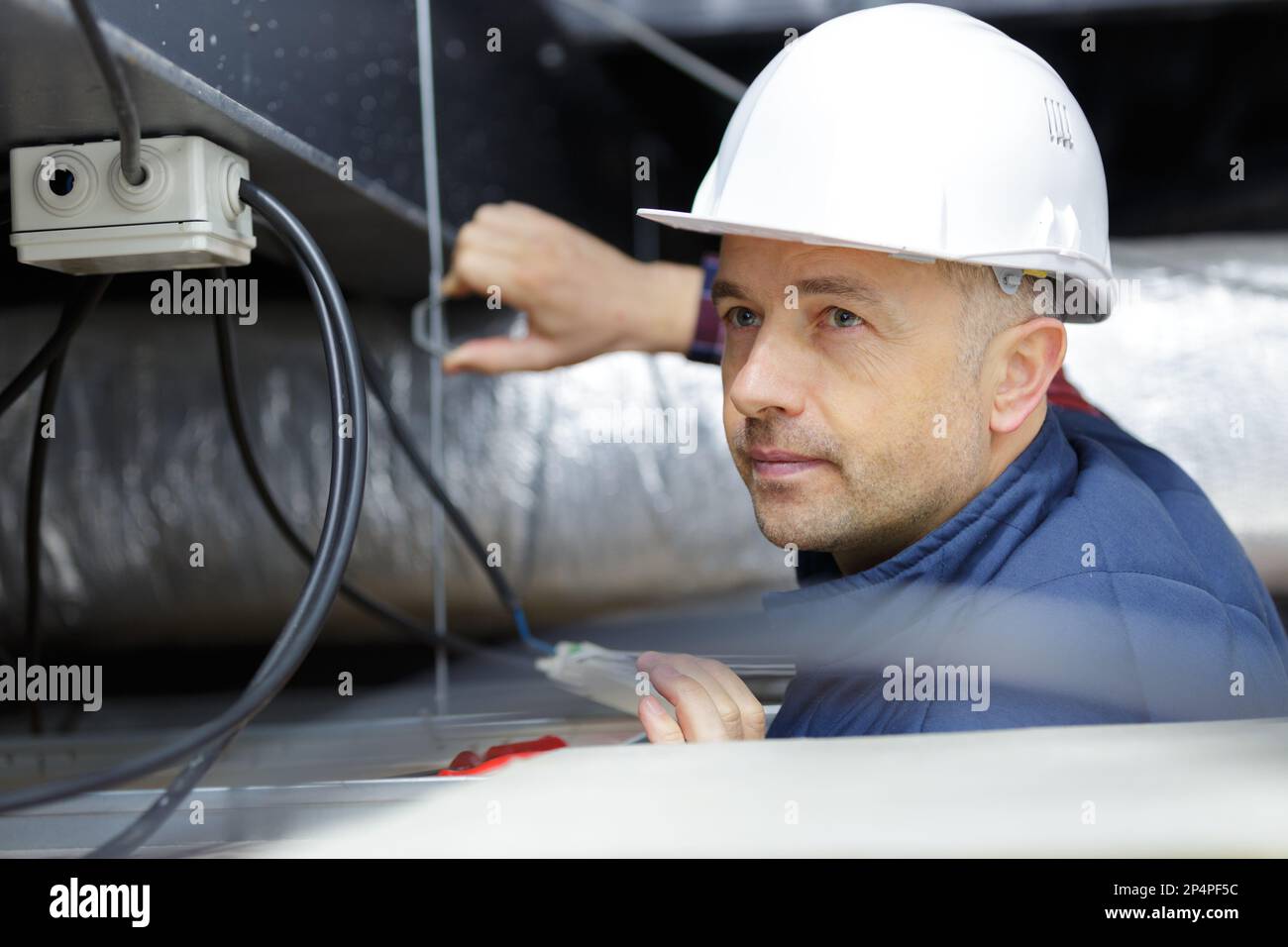 l'employé inspecte le câblage pour la ventilation Banque D'Images