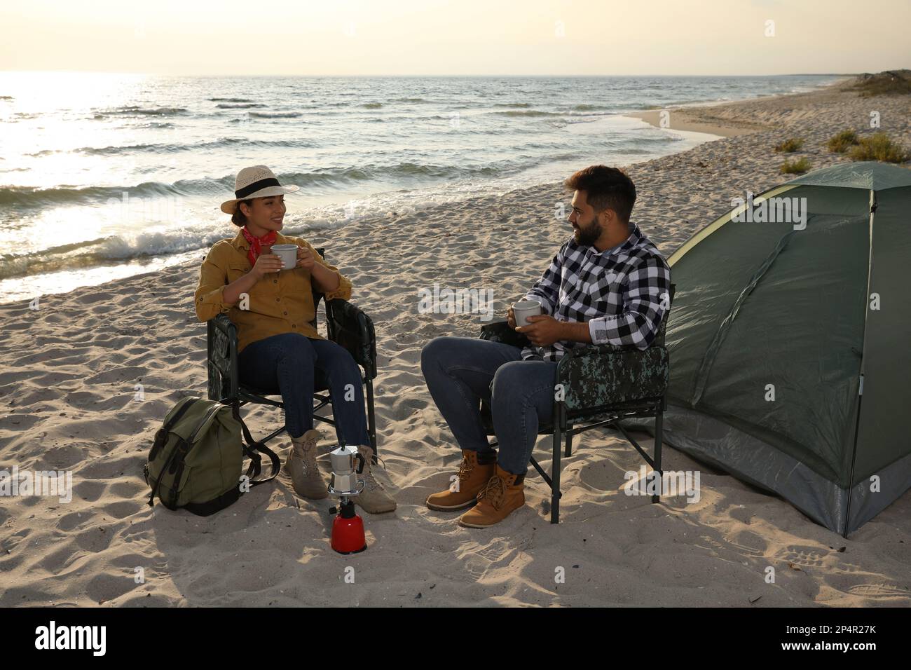 Couple avec boissons chaudes près de tente de camping sur la plage Banque D'Images