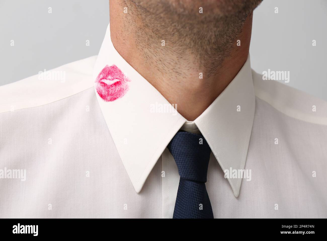 Homme en chemise avec une marque de baiser rouge à lèvres sur fond blanc,  gros plan Photo Stock - Alamy