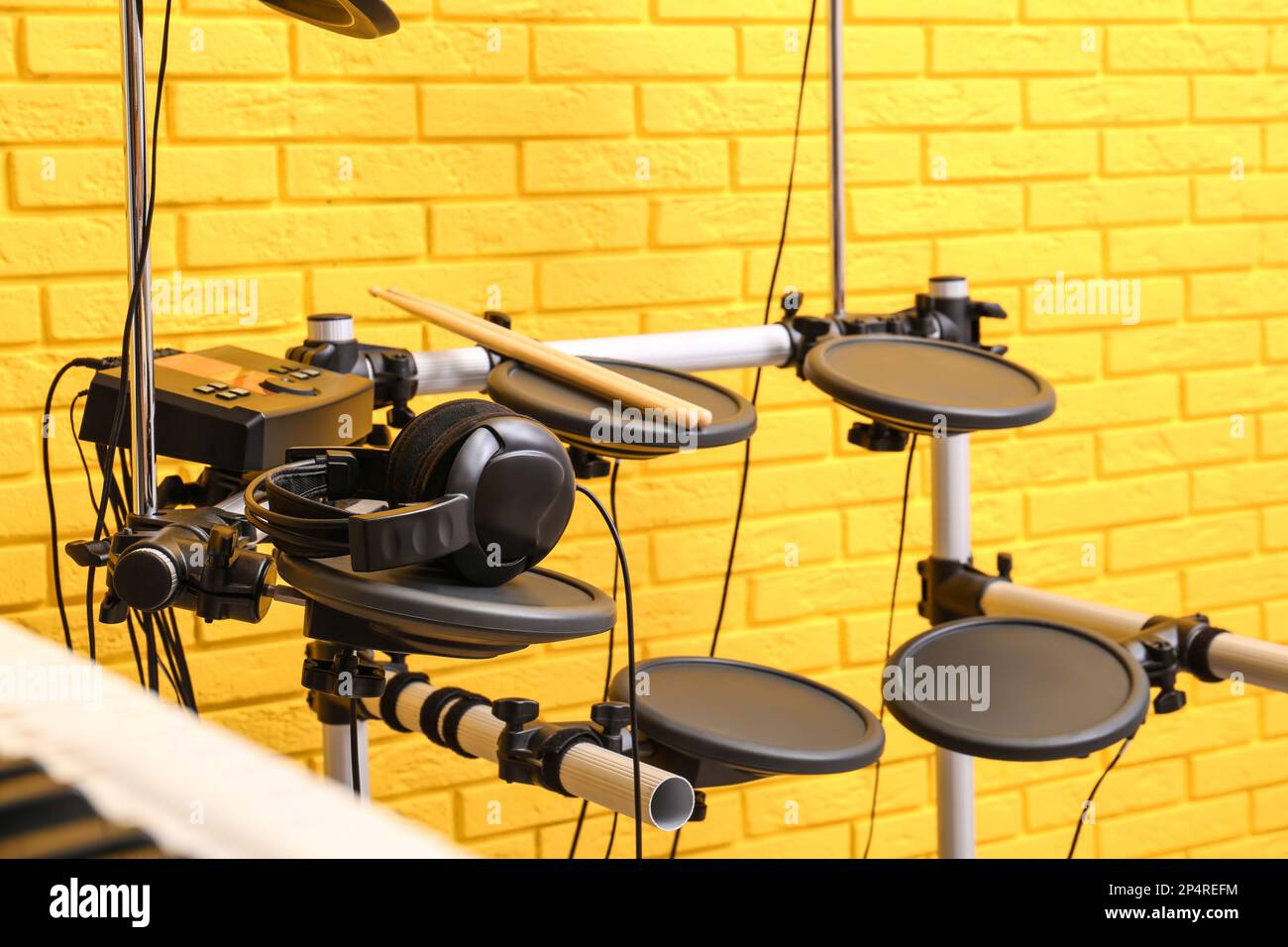 Kit de tambour électronique moderne près du mur de briques jaunes à l'intérieur. Instrument de musique Banque D'Images