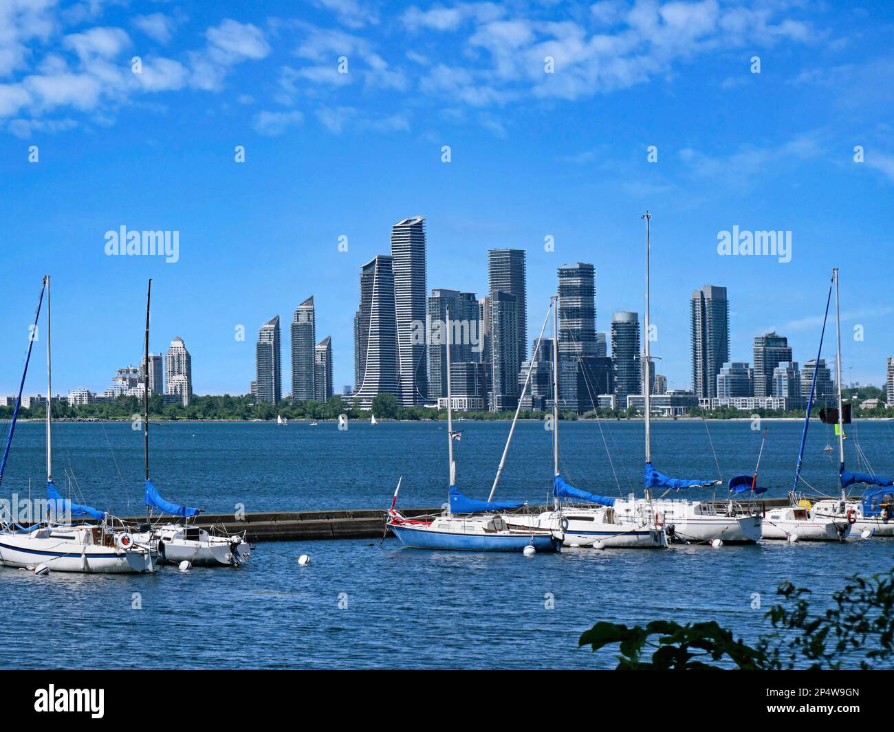 De petits voiliers se sont joints au brise-lames du lac Ontario, avec des gratte-ciels de construction d'appartements de banlieue de Toronto en arrière-plan Banque D'Images