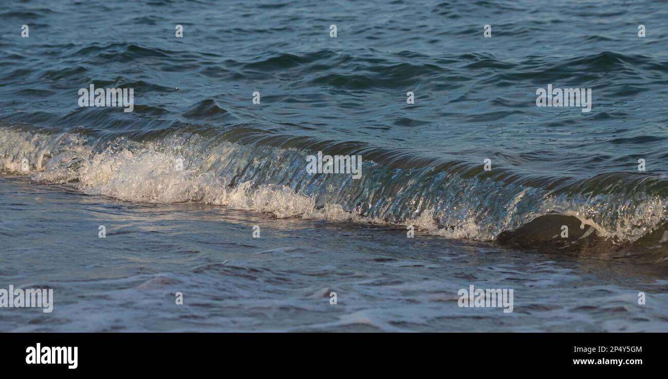 Une grande et forte onde de tempête de couleur turquoise avec des éclaboussures de mousse blanche coule et se brise sur le rivage. Banque D'Images