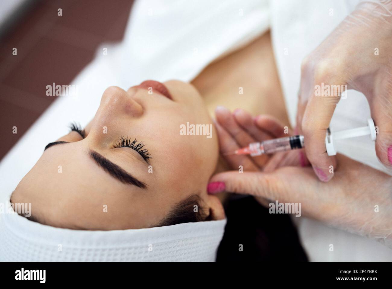 Injections de beauté. Une femme cosmétologue en gants transparents fait une injection dans la mâchoire inférieure de son client. Traitement à l'acide hyaluronique. Introduction Banque D'Images
