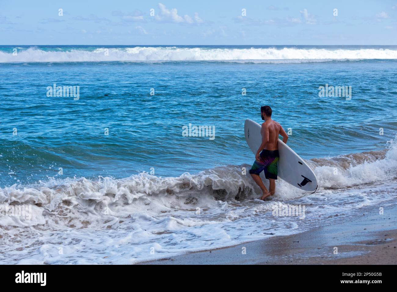 Saint-Gilles les bains, la Réunion - 25 juin 2017: Surfeur entrant dans l'eau pour profiter des vagues du solstice d'été malgré l'interdiction du surf à ' Banque D'Images