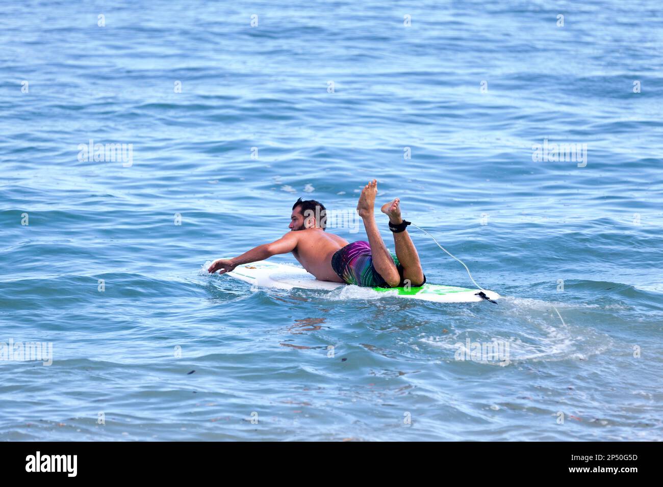 Saint-Gilles les bains, la Réunion - 25 juin 2017 : surfeur nageant à son bord pour atteindre les vagues du solstice d'été malgré l'interdiction de surfer a Banque D'Images