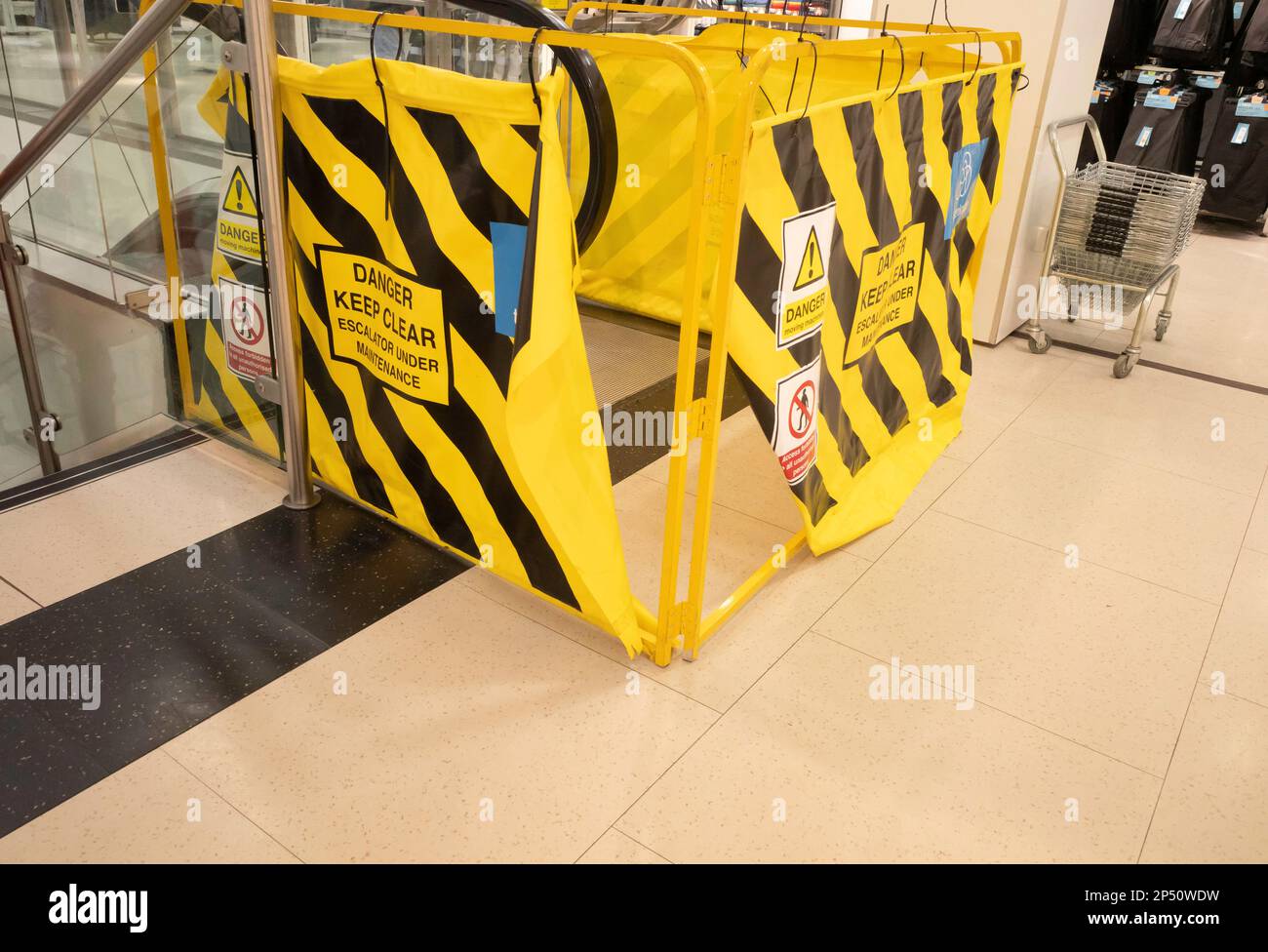 Le haut de l'escalier roulant d'un grand magasin est fermé par des barrières jaunes pendant les travaux d'entretien Banque D'Images