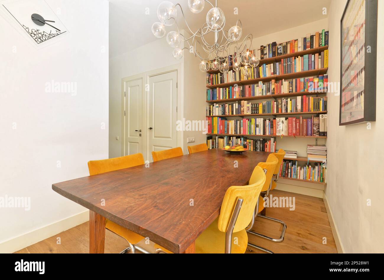 Amsterdam, pays-Bas - 10 avril 2021 : une salle à manger avec quelques livres sur les étagères et une chandel dans la table est entourée de chaises jaunes Banque D'Images