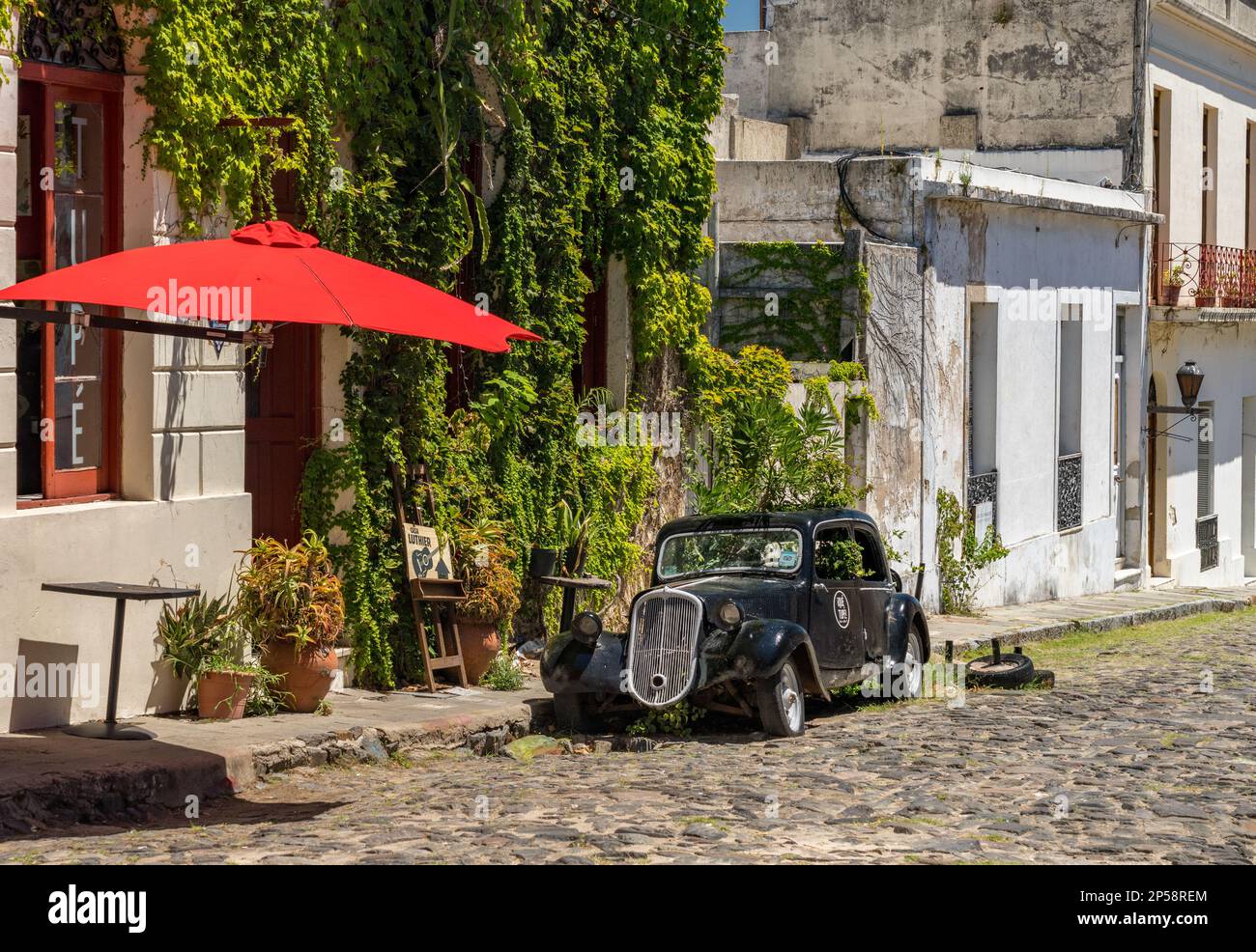 Colonia del Sacramento, Uruguay - 5 février 2023 : ancienne voiture ancienne près d'un bar ou d'un café local dans une rue pavée Banque D'Images