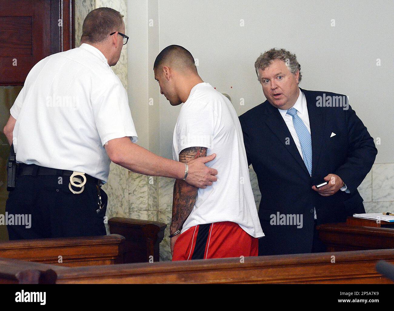 Former New England Patriots tight end Aaron Hernandez, center, is led away, as his attorney Michael Fee speaks to him, right, after arraignment in Attleboro District Court Wednesday, June 26, in Attleboro, Mass. Hernandez was charged with murdering Odin Lloyd, a 27-year-old semi-pro football player for the Boston Bandits, whose body was found June 17 in an industrial park in North Attleborough, Mass. (AP Photo/The Sun Chronicle, Mike George, Pool) Banque D'Images