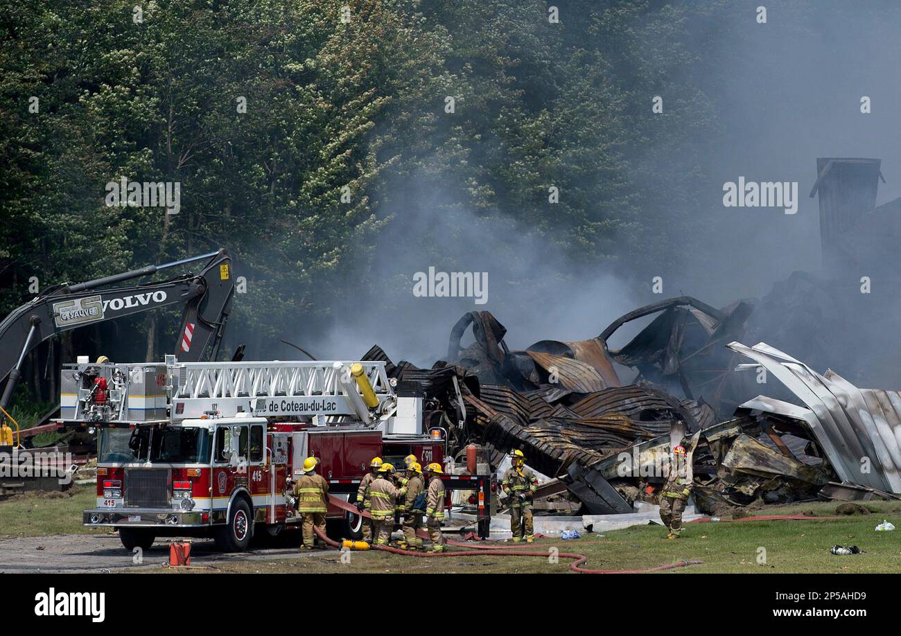 Emergency workers survey the scene as smoke billows from the smoldering B.E.M. fireworks factory in Coteau du Lac, Que., Thursday, June 20, 2013. Two people were killed in a massive explosion at the fireworks warehouse that rattled homes and sent up a cloud of smoke that could be seen for miles outside Montreal. (AP Photo/The Canadian Press, Graham Hughes) Banque D'Images