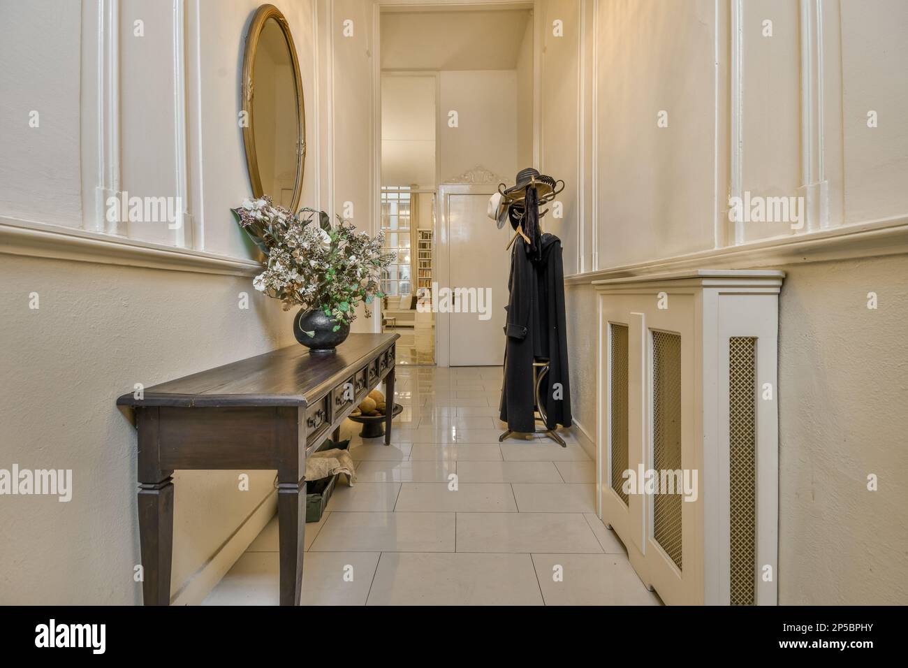 un long couloir avec un miroir sur le mur et un porte-manteau dans le coin à côté de la table de la console Banque D'Images