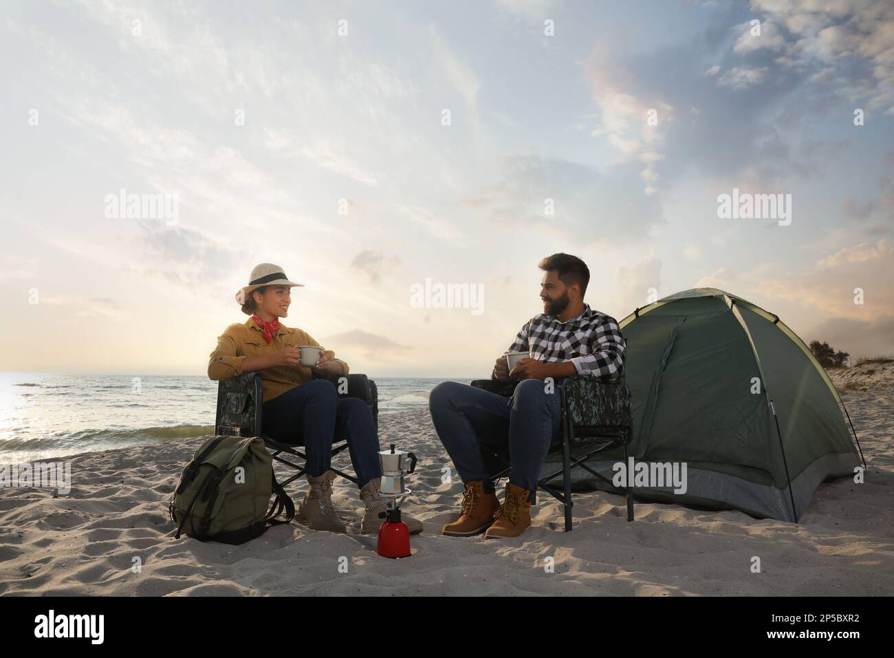 Couple avec boissons chaudes près de tente de camping sur la plage Banque D'Images