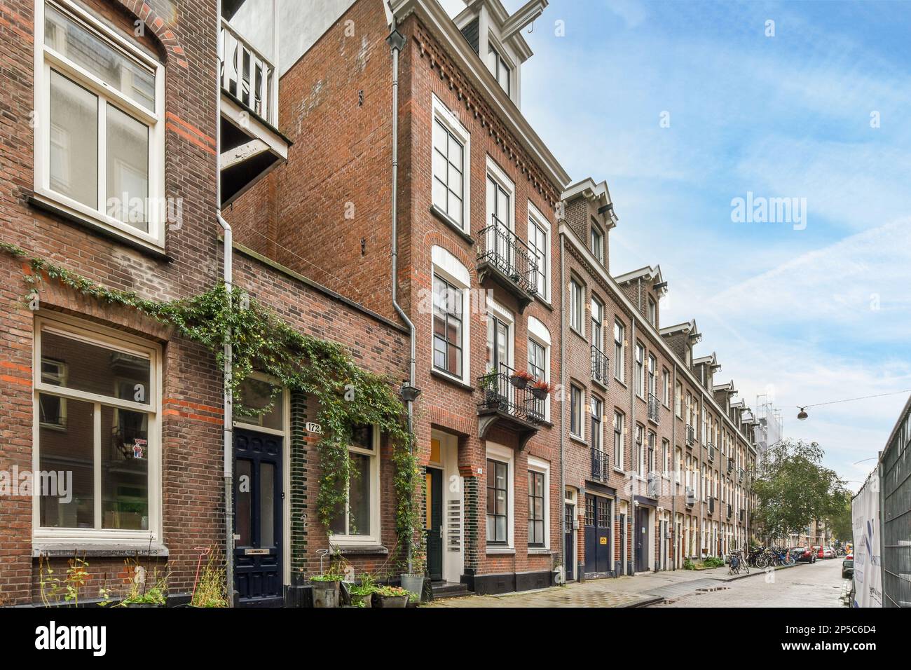 Amsterdam, pays-Bas - 10 avril 2021 : rue de la ville avec des bâtiments en briques des deux côtés et des plantes vertes qui poussent dans les allées le long de la rue Banque D'Images