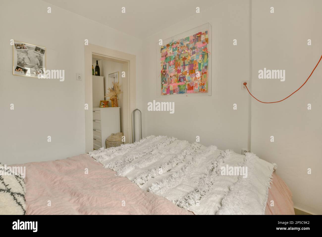 Amsterdam, pays-Bas - 10 avril 2021 : un lit avec draps blancs et couette rose à côté du lit est une peinture sur le mur derrière lui Banque D'Images