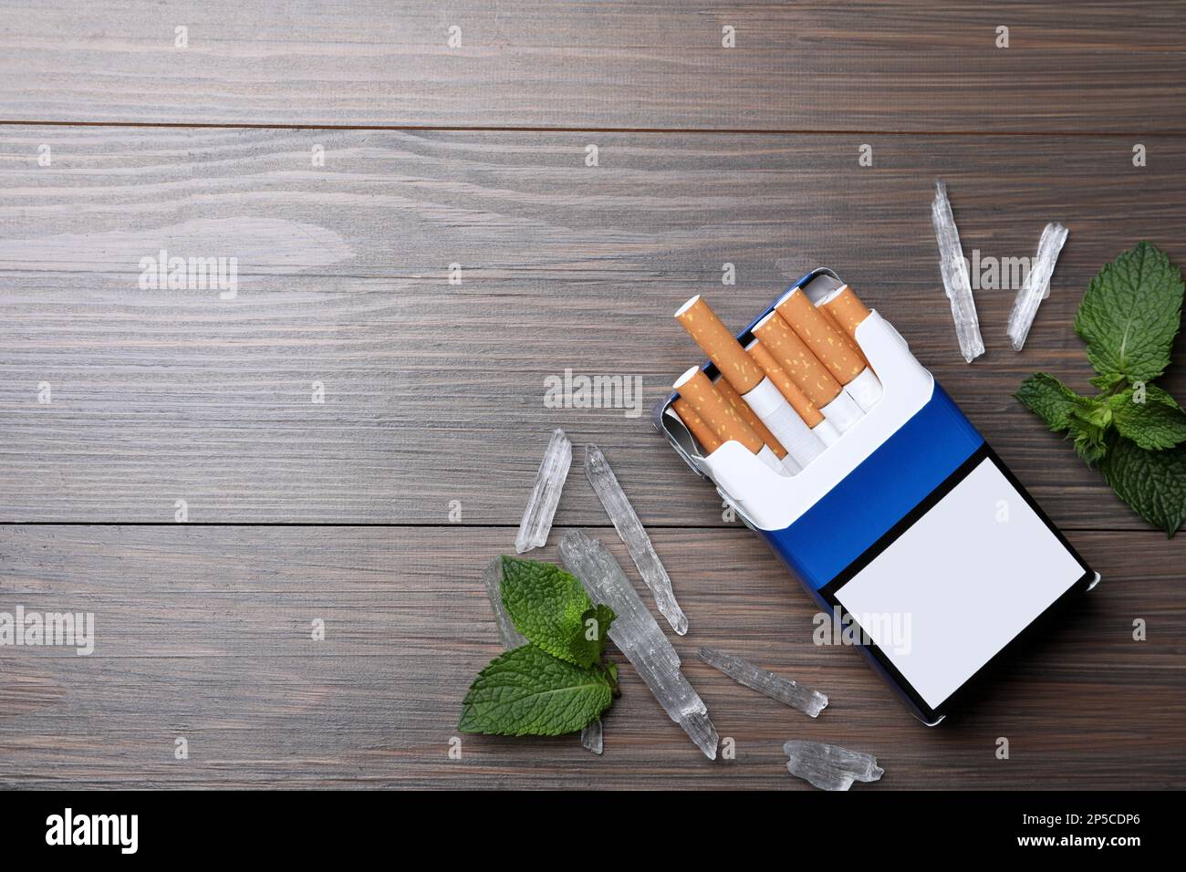 Paquet de cigarettes, de cristaux de menthol et de menthe sur table en bois, plat. Espace pour le texte Banque D'Images