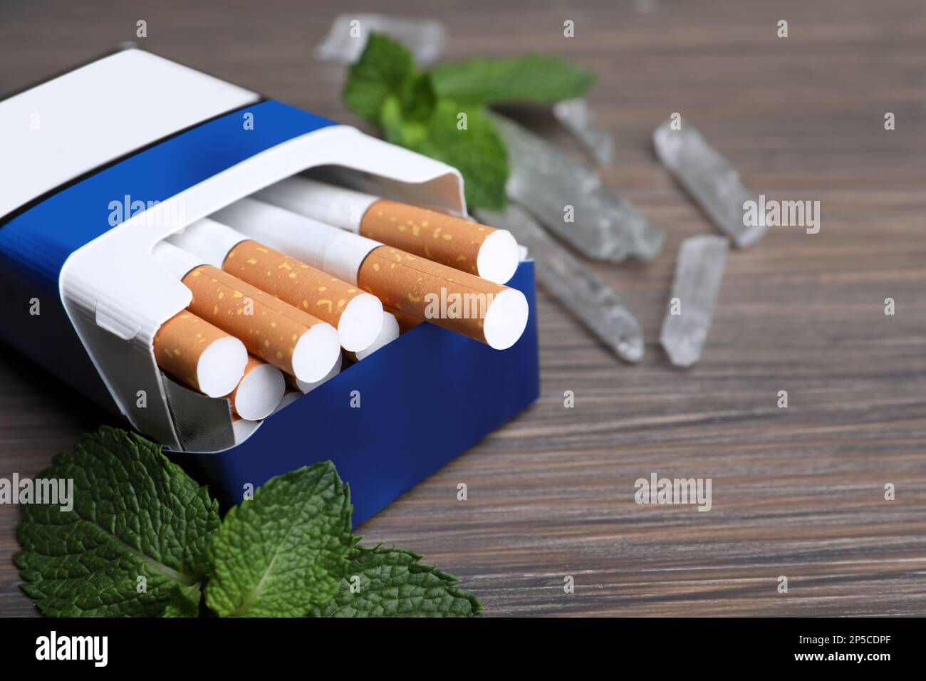 Paquet de cigarettes, de cristaux de menthol et de menthe sur table en bois, gros plan. Espace pour le texte Banque D'Images