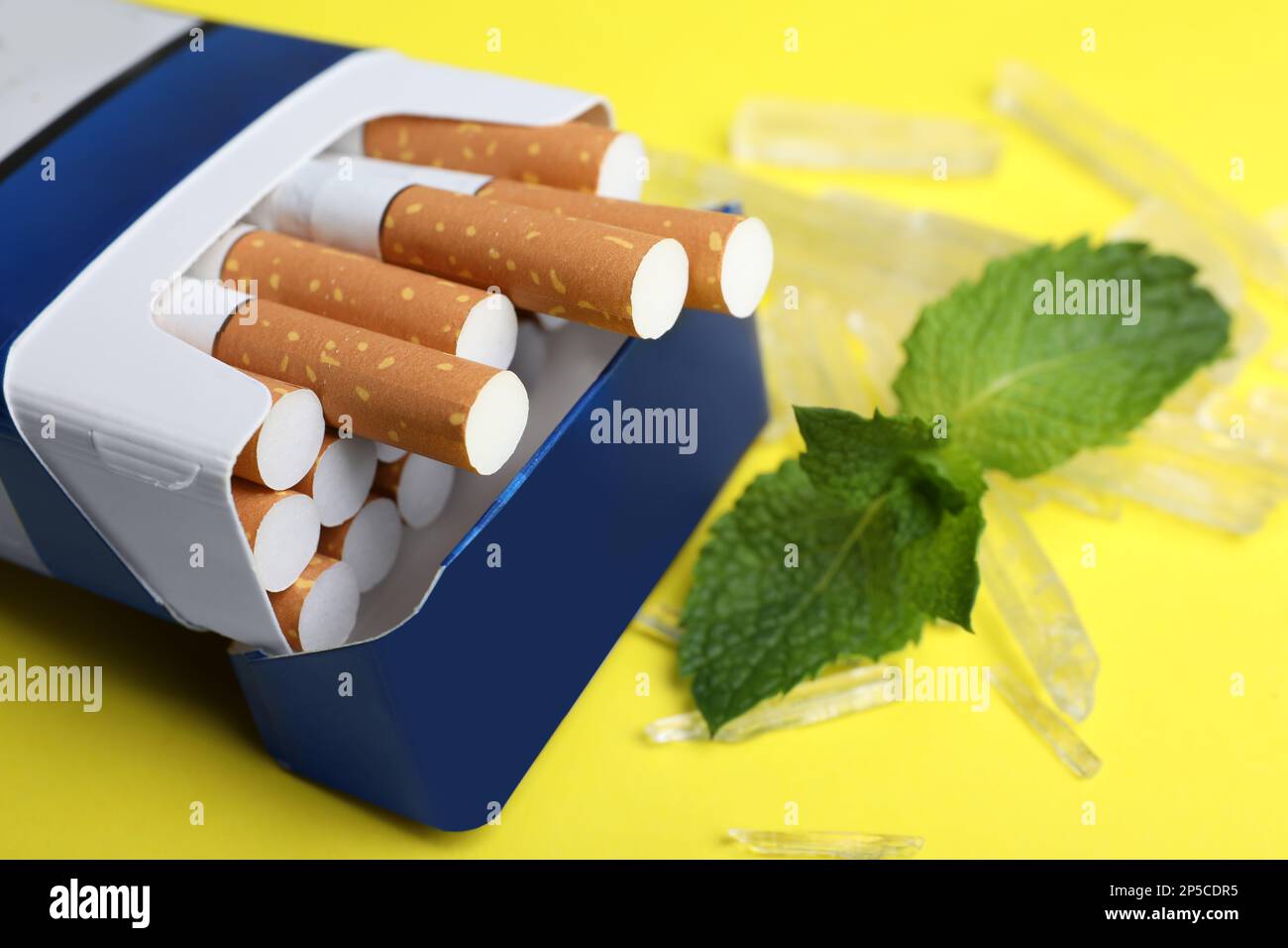 Paquet de cigarettes, de cristaux de menthol et de menthe sur fond jaune, gros plan Banque D'Images