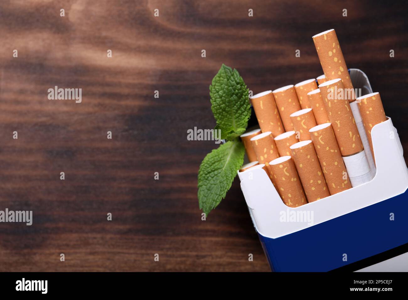 Paquet de cigarettes de menthol et feuilles de menthe sur table en bois, plat. Espace pour le texte Banque D'Images