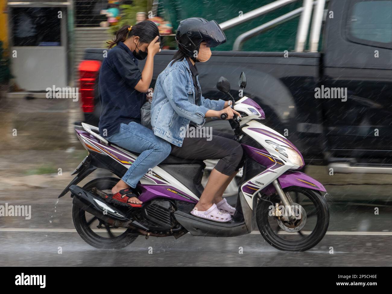 SAMUT PRAKAN, THAÏLANDE, SEP 21 2022, deux femmes conduisent une moto sous la pluie Banque D'Images