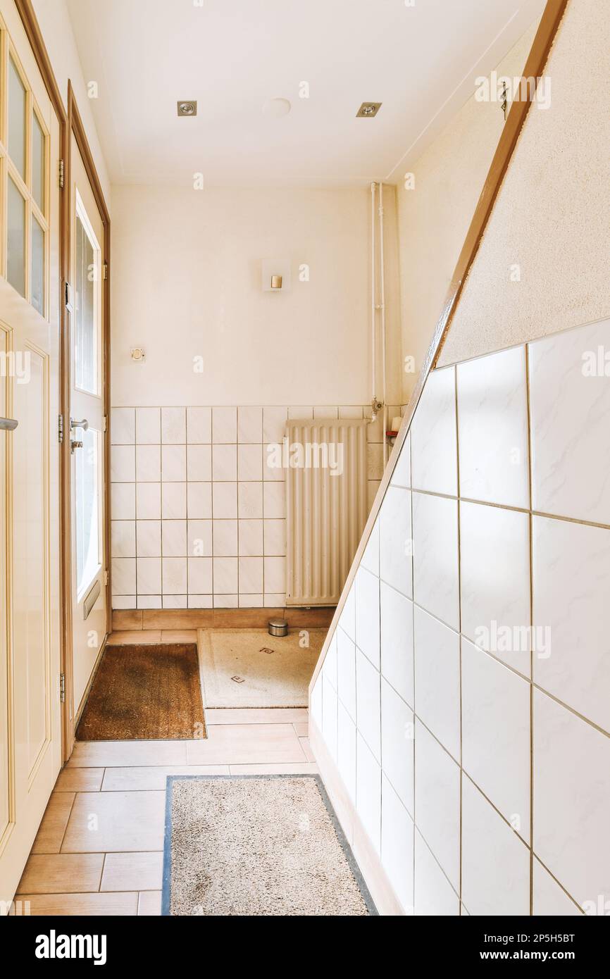 une salle de bains avec carrelage blanc sur les murs et le sol en face de la baignoire est montrée à droite Banque D'Images