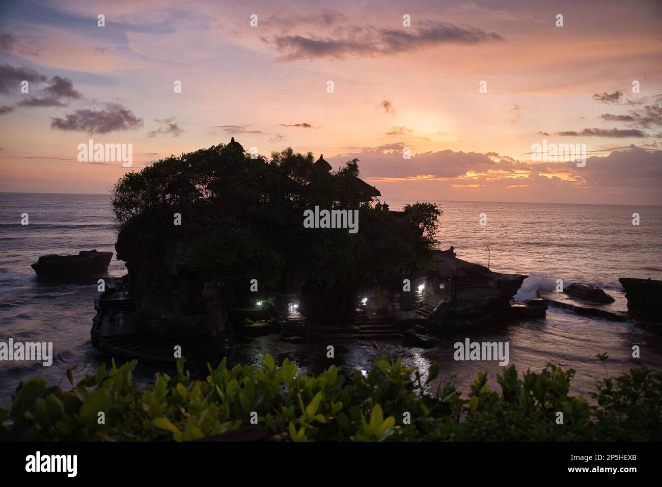 Photo de tout le temple de Pura Tanah Lot, prise d'en haut complètement entouré par la mer, avec un ciel de coucher de soleil en arrière-plan. Banque D'Images