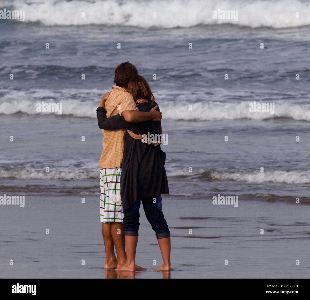 Meg Strange, right, wife of Adam Strange is comforted by friend Simon Shephard, as people gather on Muriwai Beach near Auckland, New Zealand, Thursday, Feb. 28, 2013, to say goodbye to Adam Strange. About 150 friends and family of Adam, 46, wrote messages to him in the sand and stepped into the water Thursday at a New Zealand beach to say goodbye after he was killed Wednesday by a large shark. (AP Photo/New Zealand Herald, Brett Phibbs) New Zealand Out, Australia Out Banque D'Images