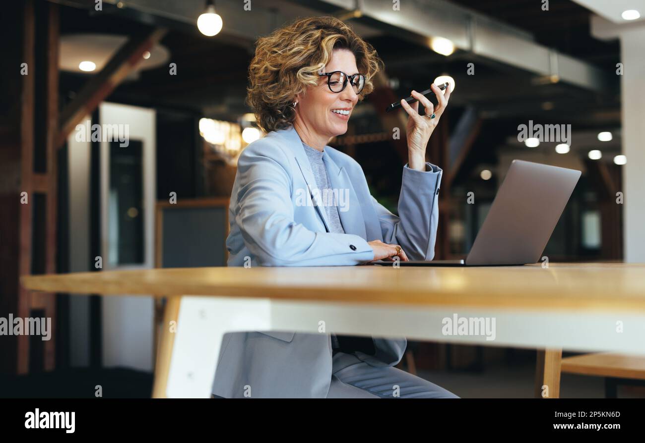 Femme parlant sur un appel téléphonique tout en travaillant sur un ordinateur portable dans un espace de coworking. femme d'affaires appelant ses clients sur un téléphone portable. Busin professionnel Banque D'Images