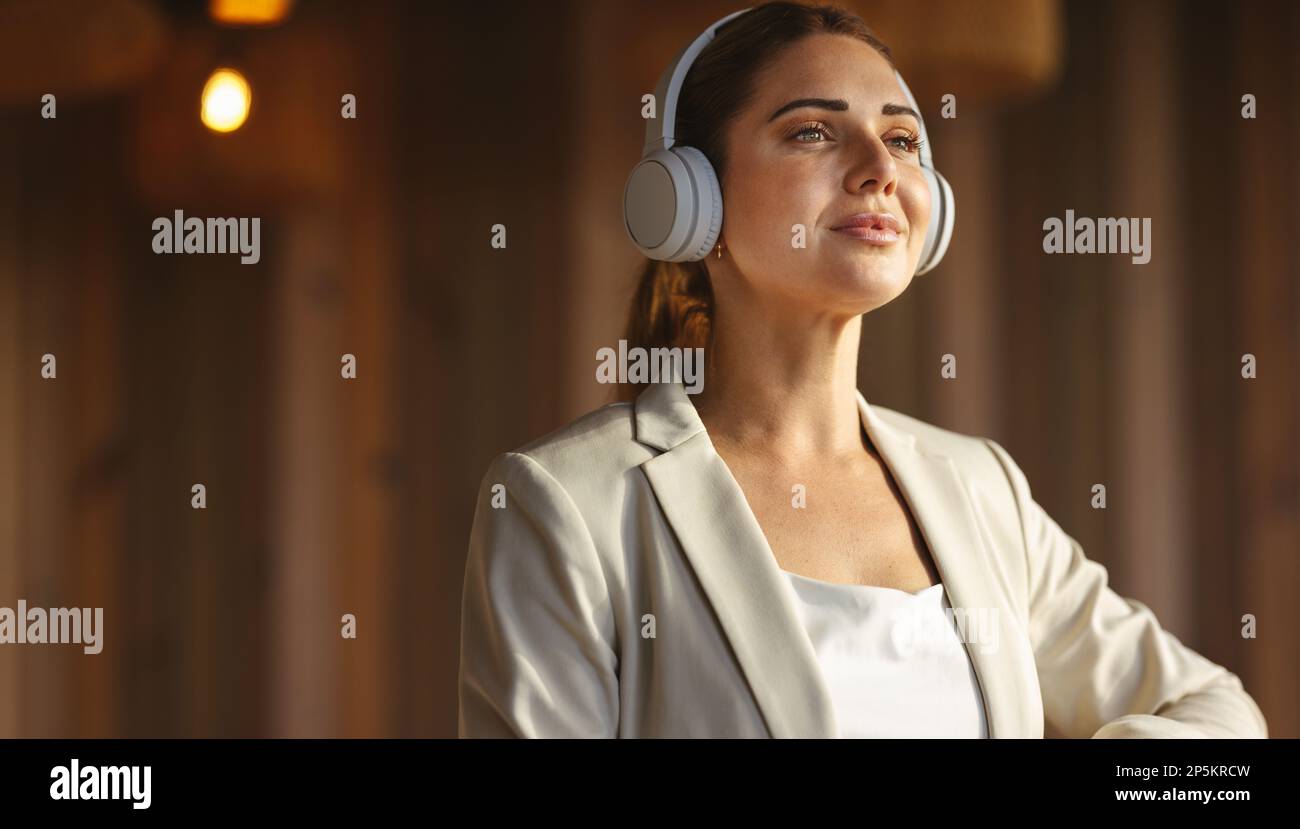 femme d'affaires portant des écouteurs sans fil dans un bureau de coworking. Femme professionnelle écoutant de la musique relaxante au travail. Banque D'Images