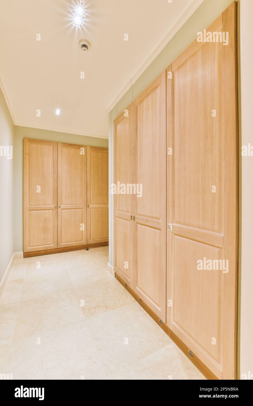une pièce vide avec des armoires en bois et un sol en marbre blanc dans la pièce est bien éclairée par une lumière encastrée Banque D'Images