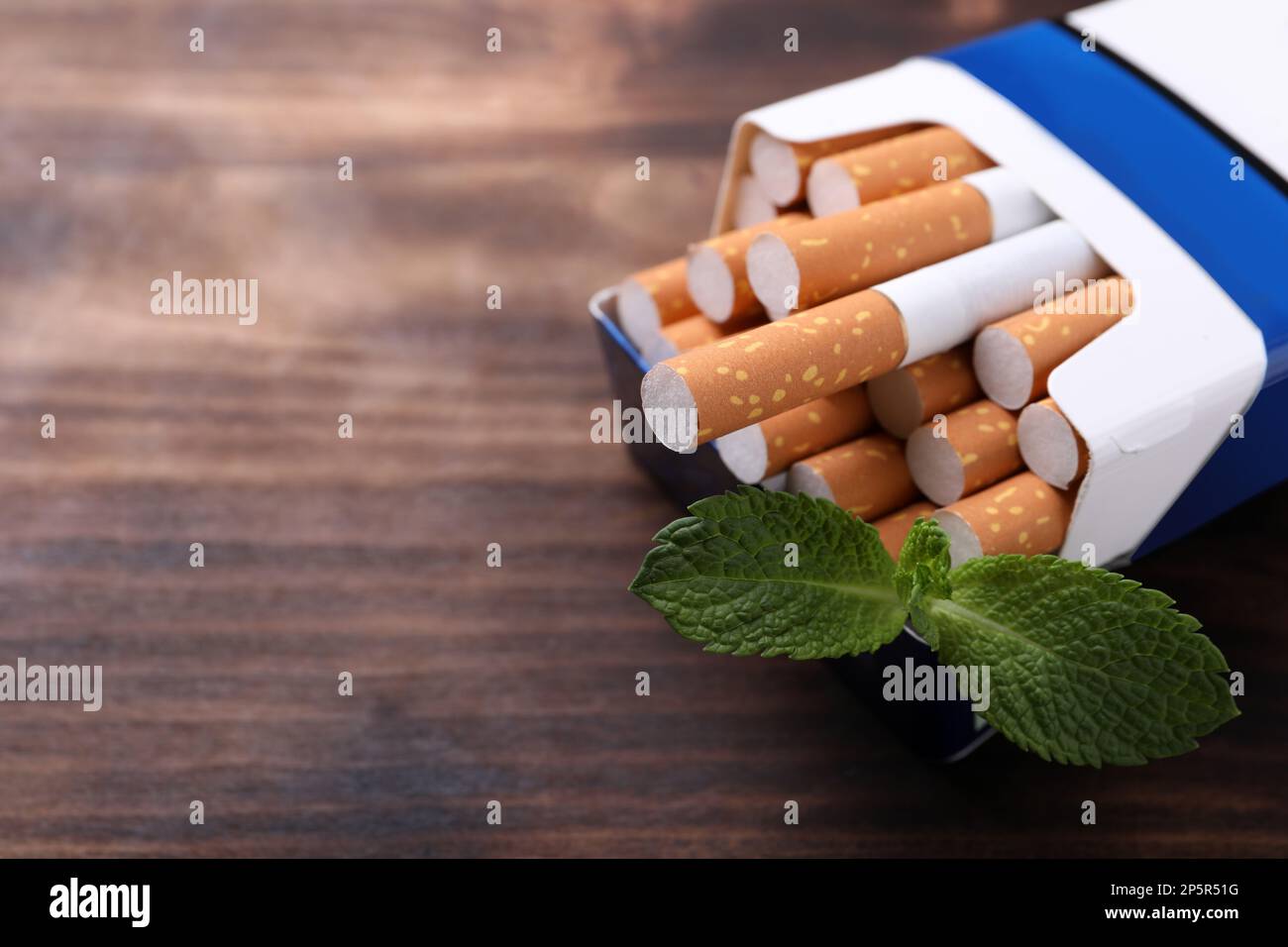 Paquet de cigarettes de menthol et de feuilles de menthe sur table en bois, gros plan. Espace pour le texte Banque D'Images