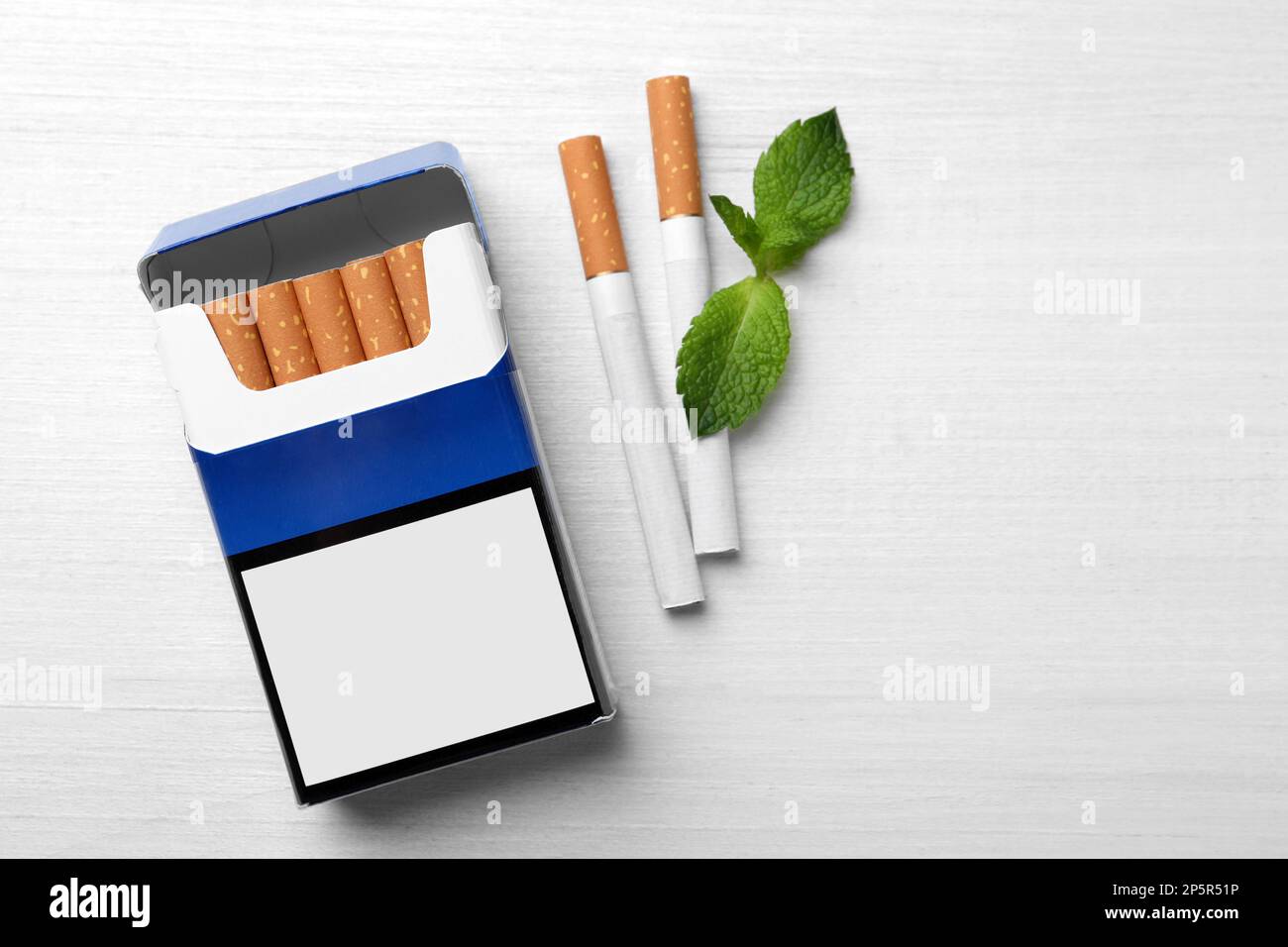 Cigarettes de menthol, paquet et menthe sur table en bois blanc, plat. Espace pour le texte Banque D'Images