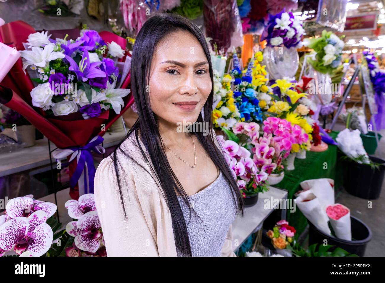 Une cliente thaïlandaise inspecte des fleurs au marché aux fleurs Pak Khlong Talat Mai, Bangkok, Thaïlande Banque D'Images