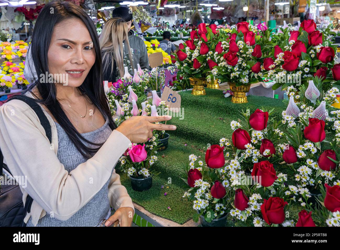 Une cliente thaïlandaise inspecte des fleurs au marché aux fleurs Pak Khlong Talat Mai, Bangkok, Thaïlande Banque D'Images