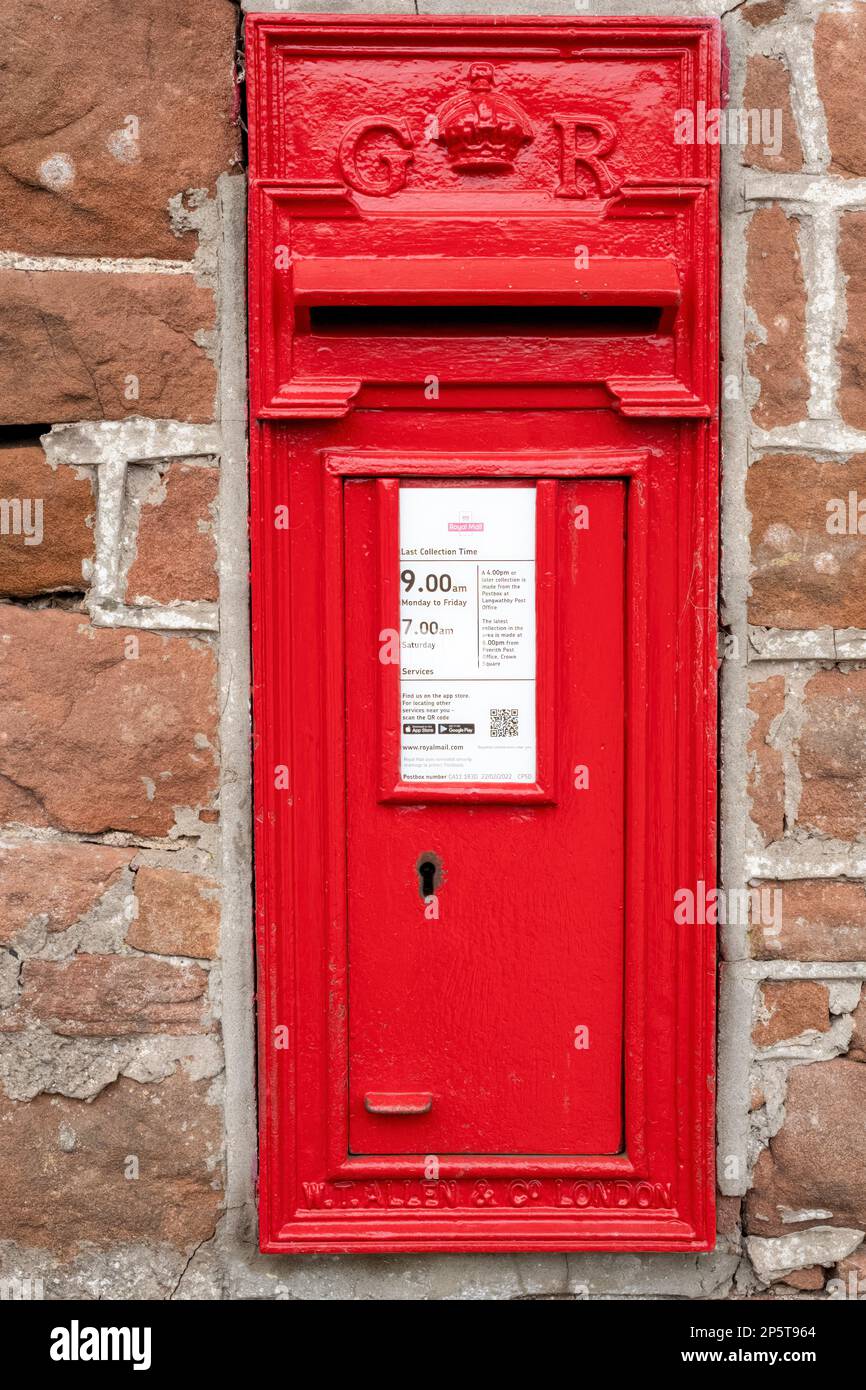 Une boîte de poteau George V montée dans un mur de grès rouge dans le village d'Edenhall, Cumbria, Royaume-Uni Banque D'Images