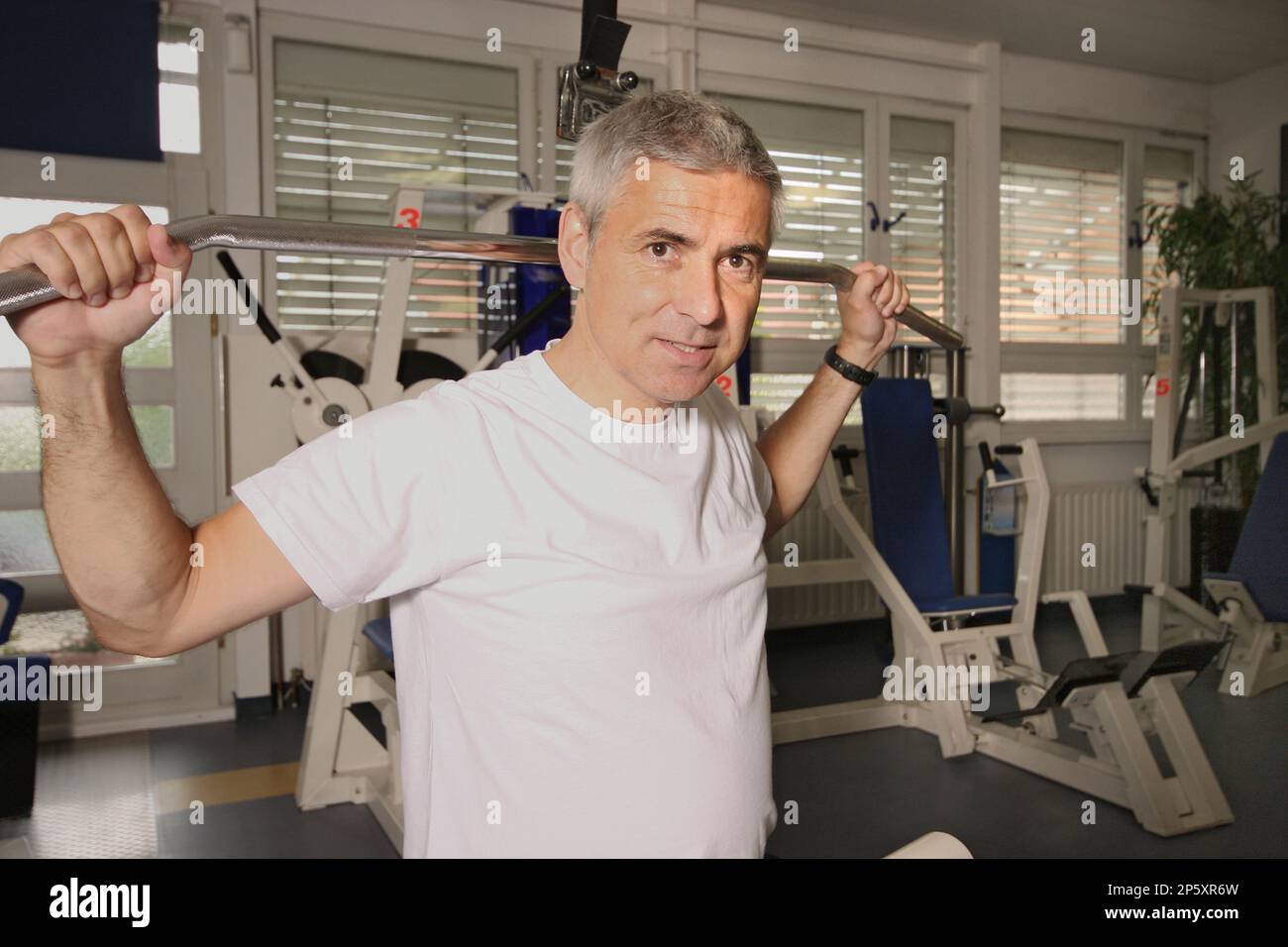 un homme âgé s'entraîne sur le pull-down de lat dans la salle de gym Banque D'Images