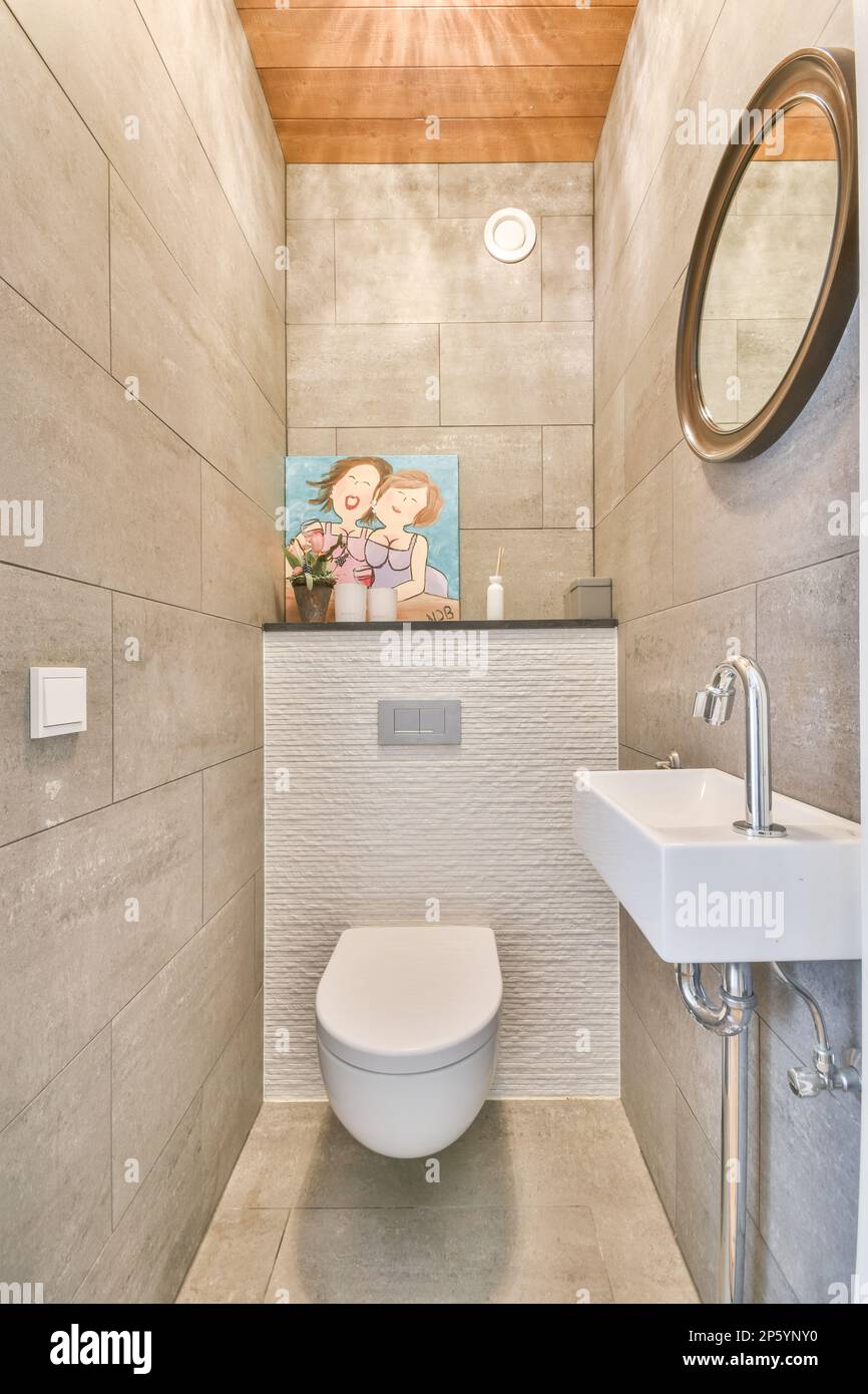 une toilette et un lavabo dans une petite salle de bains avec des lambris  sur le plafond au-dessus est une peinture du visage d'une femme Photo Stock  - Alamy