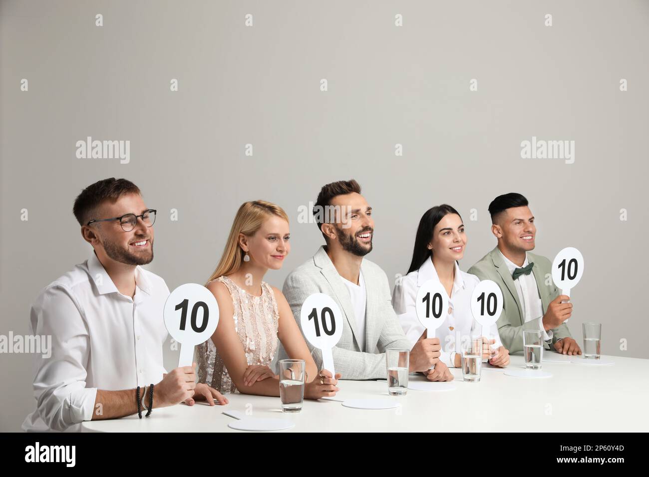 Panel de juges portant des panneaux avec le score le plus élevé à la table sur fond beige Banque D'Images