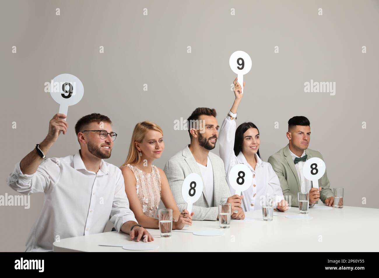 Panel de juges présentant différents signes de score à la table sur fond beige Banque D'Images