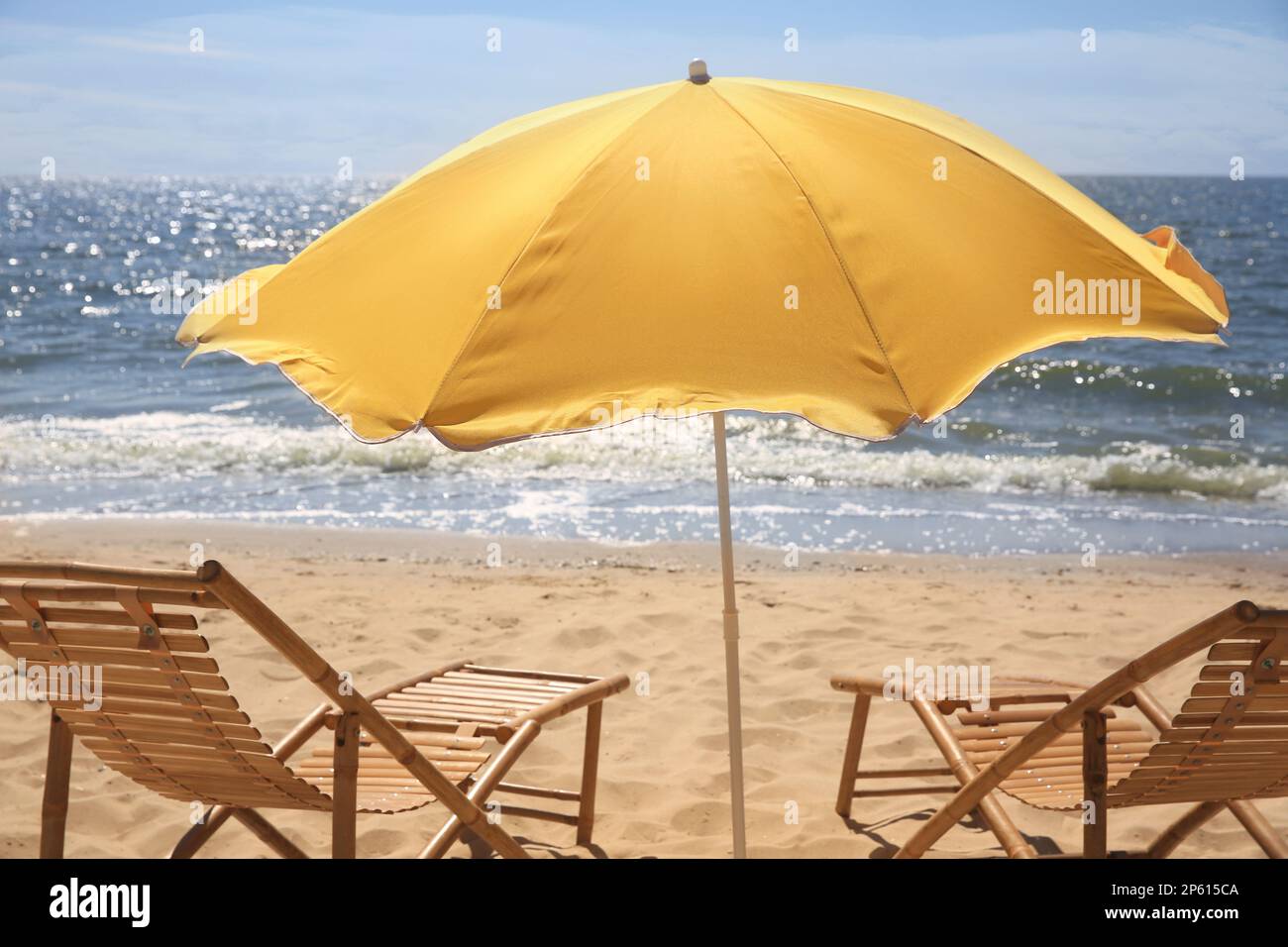 Parasol orange et chaises longues sur un bord de mer sablonneux Banque D'Images